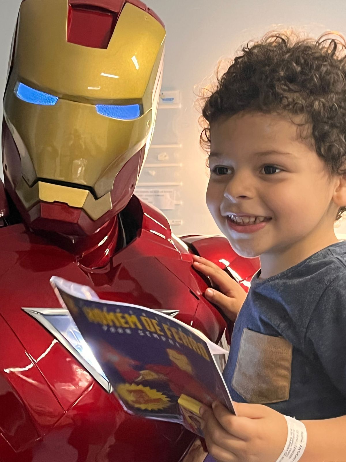 Menino sorrindo ao lado do Coração de Aço segurando a revista do projeto
