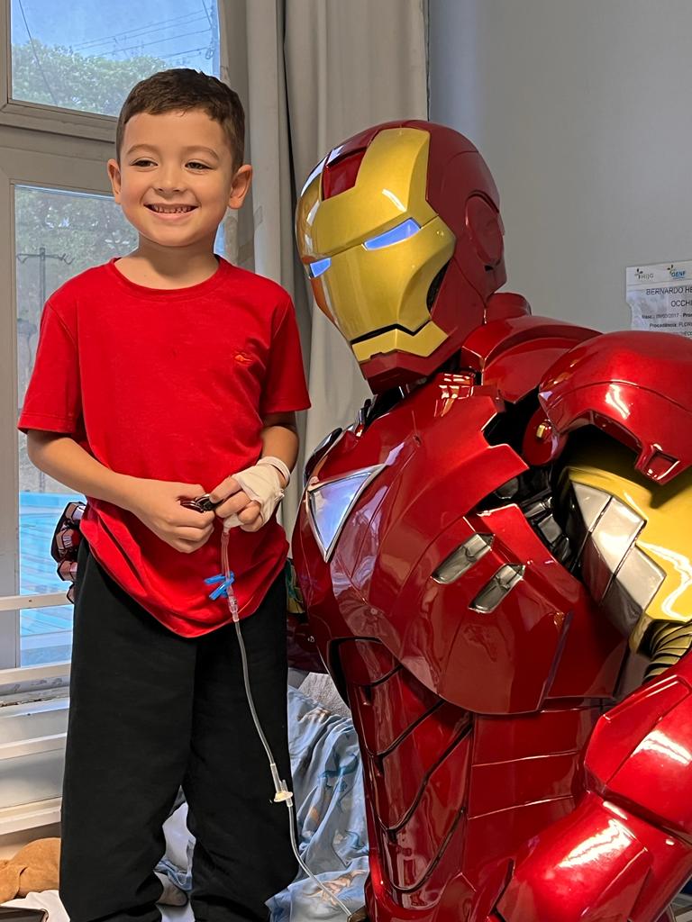 Menino de camiseta vermelha sorrindo ao lado do Coração de Aço