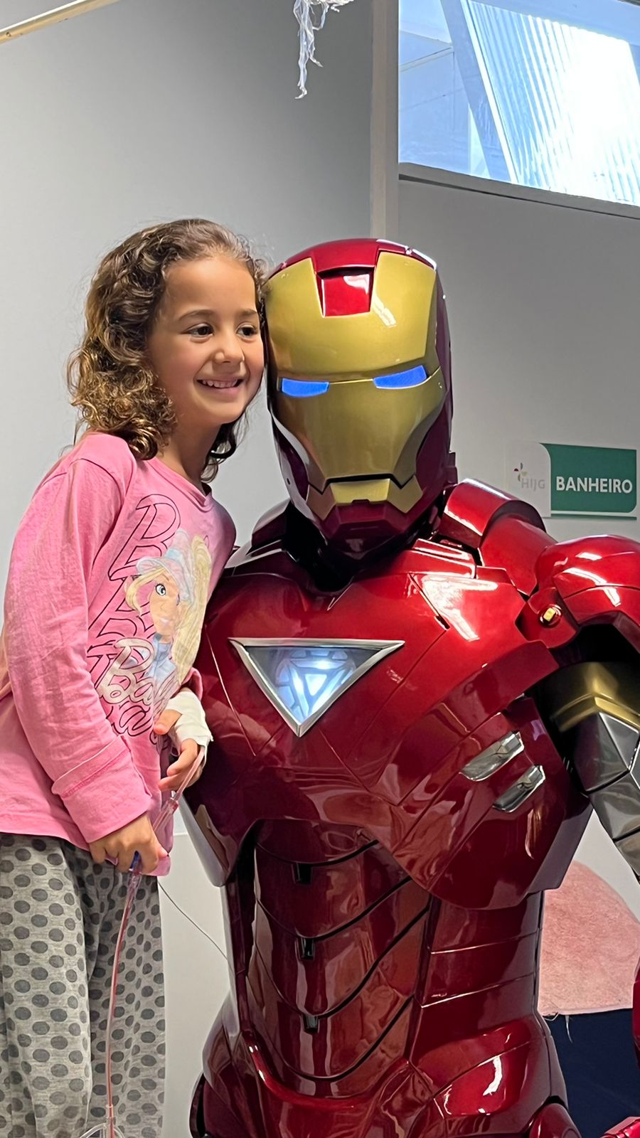 Menina sorrindo ao lado do Coração de Aço no hospital